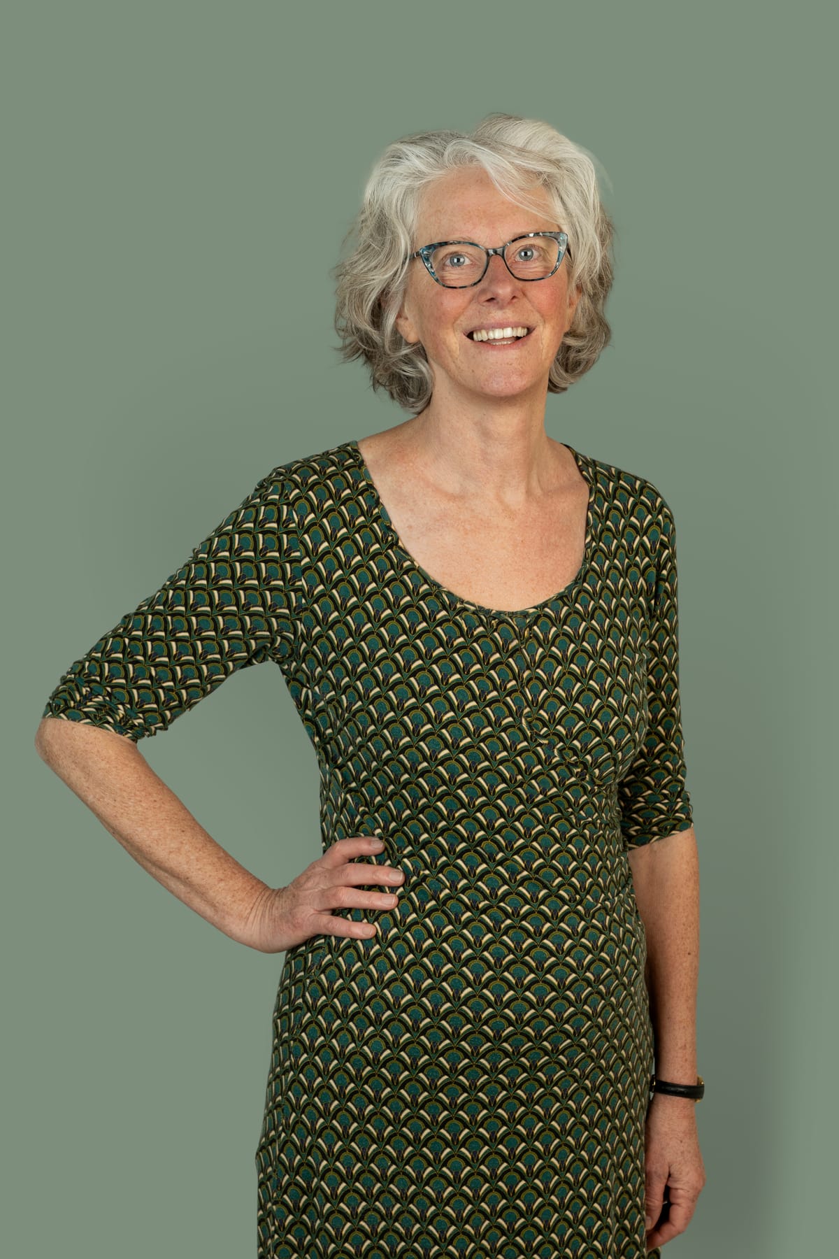 Saskia Niessink, docent Nederlands en NT2, lachend voor een saliegroene achtergrond